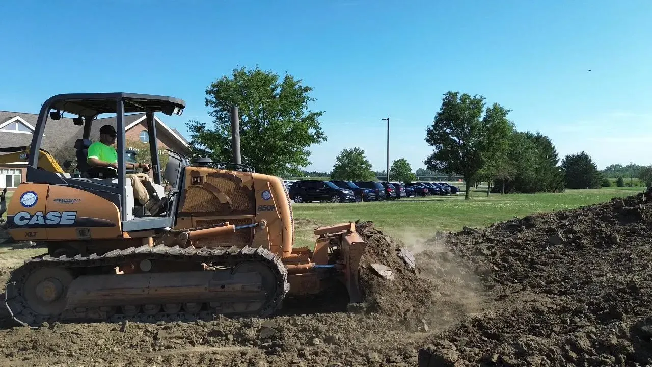 a bulldozer pushing dirt into a bigger pile