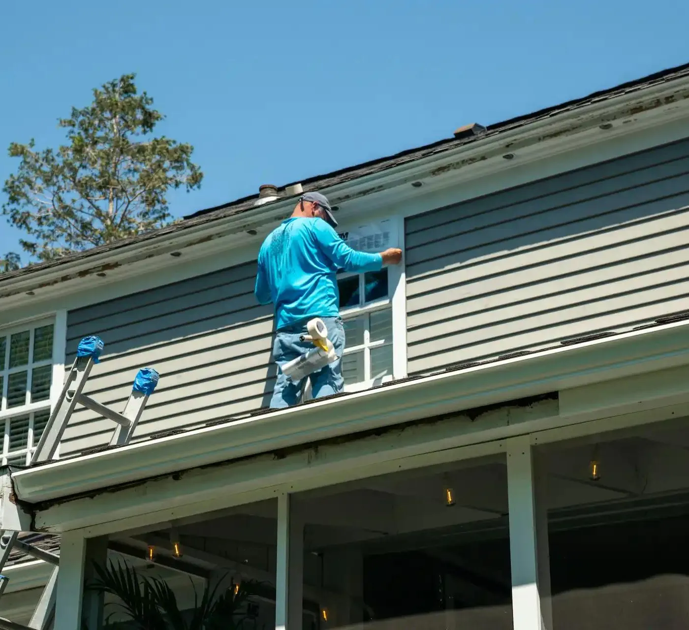 worker painting facade and window frame of a house