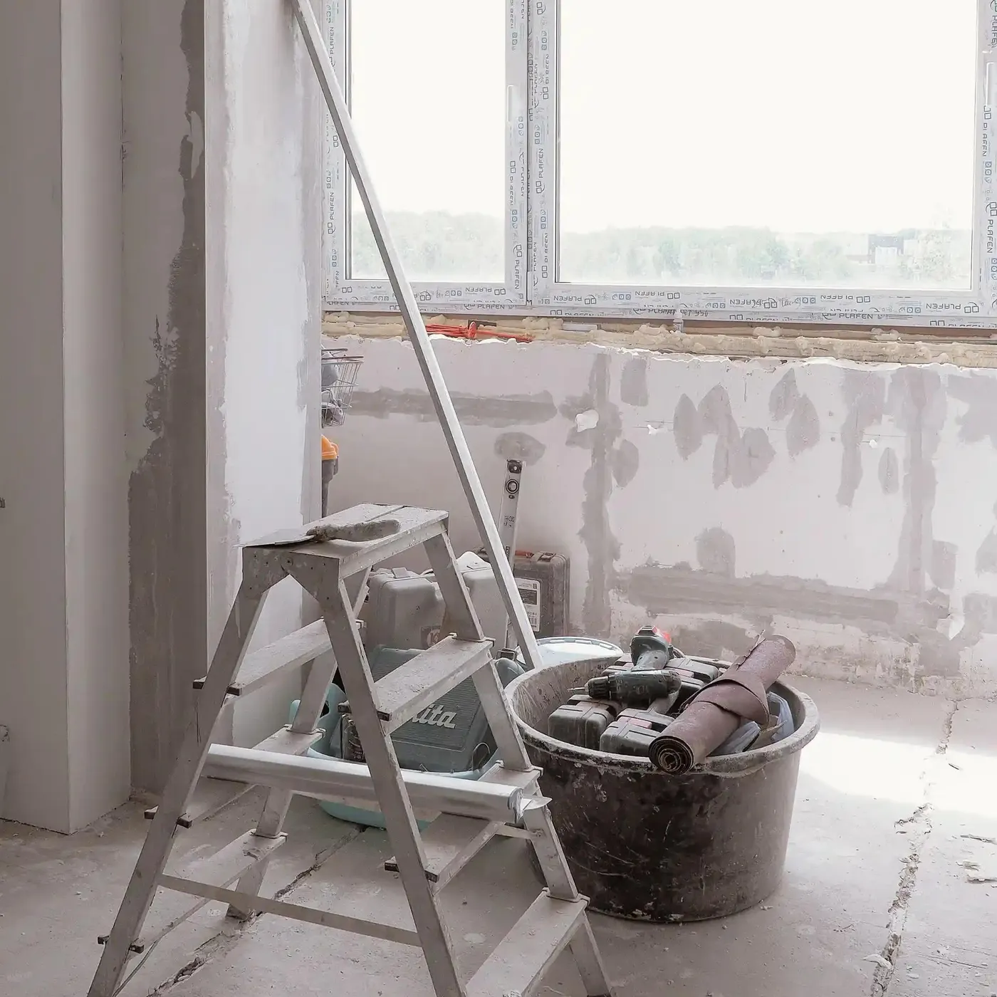 equipment and supplies near a window with bare walls ready for remodel