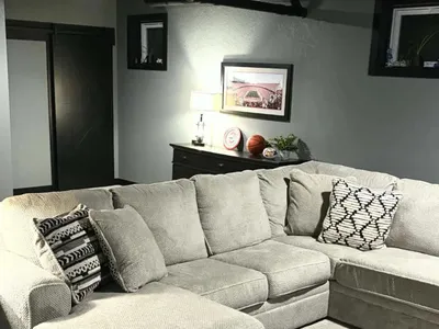 image with light gray sectional cloth couch, neutral warm gray walls, black framed windows and sliding barn door