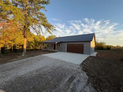 new rural home construction under a tree as sun sets